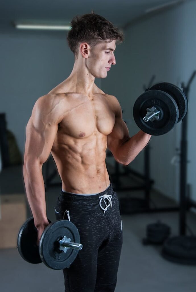 Muscular young man lifting dumbbells in a gym, showcasing strength and fitness.