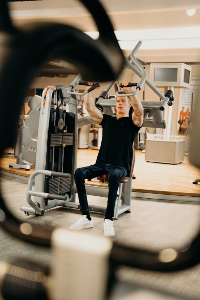 An adult man performing a workout on a fitness machine in a modern indoor gym.