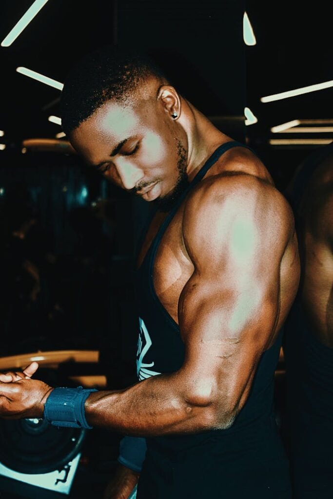 Black man demonstrating muscular physique in gym, highlighting strength and fitness.