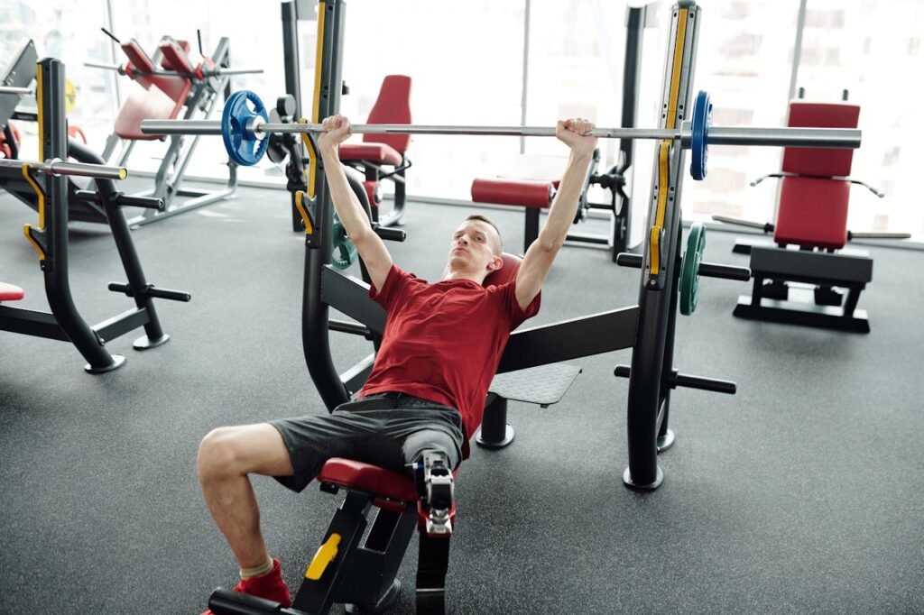 A young man with a prosthetic leg lifting weights in a modern gym, showcasing determination and strength.