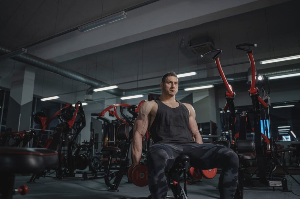 Strong muscular man lifting dumbbells in a gym setting, showcasing power and fitness.