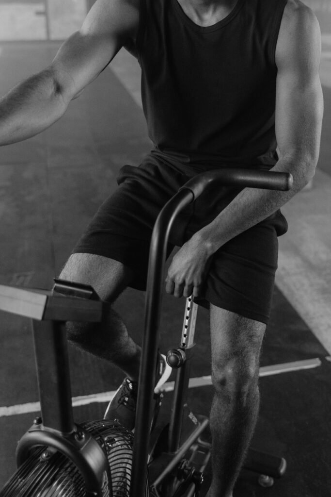 Monochrome image of a man on exercise bike, focused workout session.